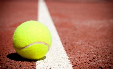 Foto primo piano di una pallina da tennis sulla riga di un campo in terra rossa
